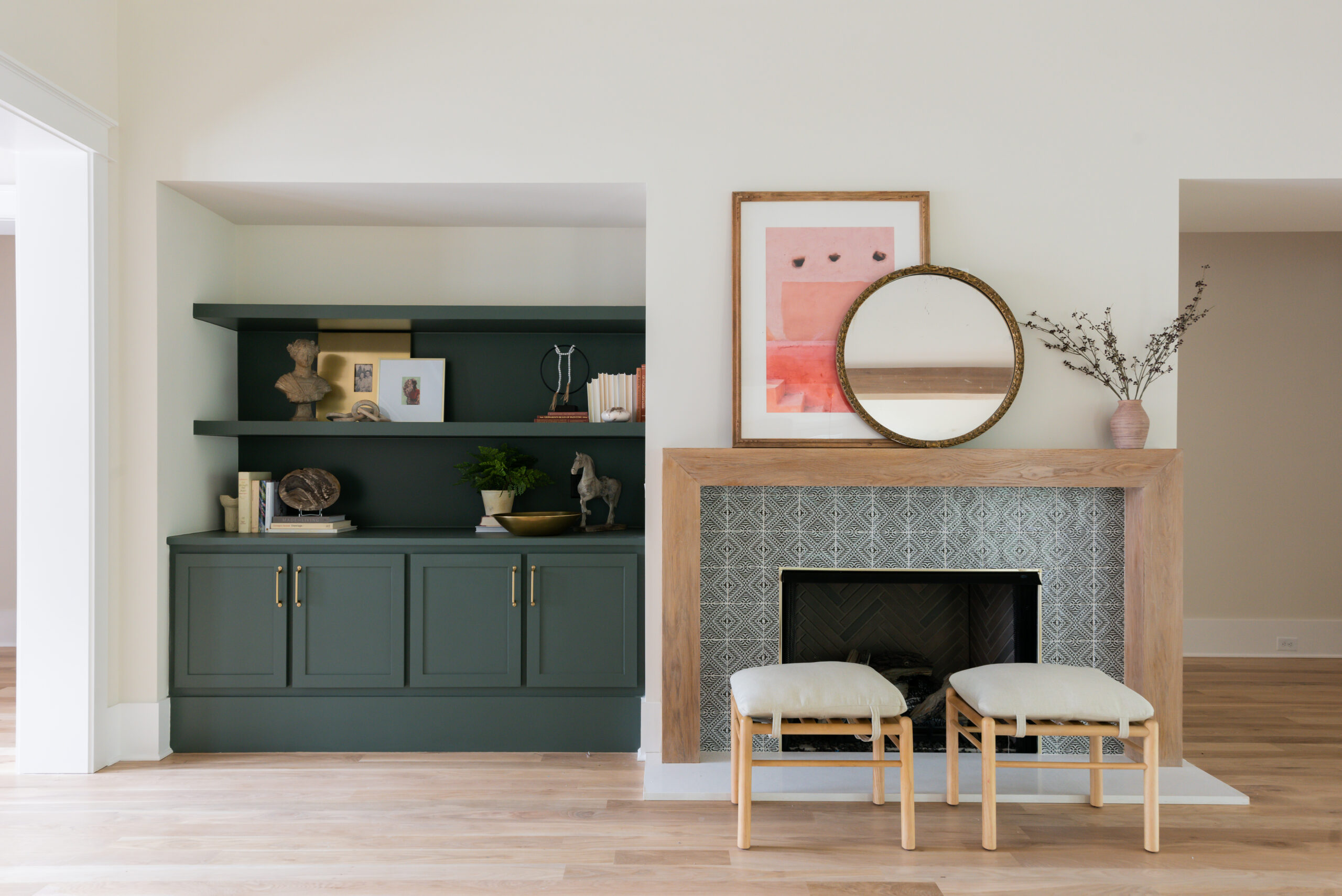 Dark green painted built-ins with wood stained mantle and patterned tile fireplace surround