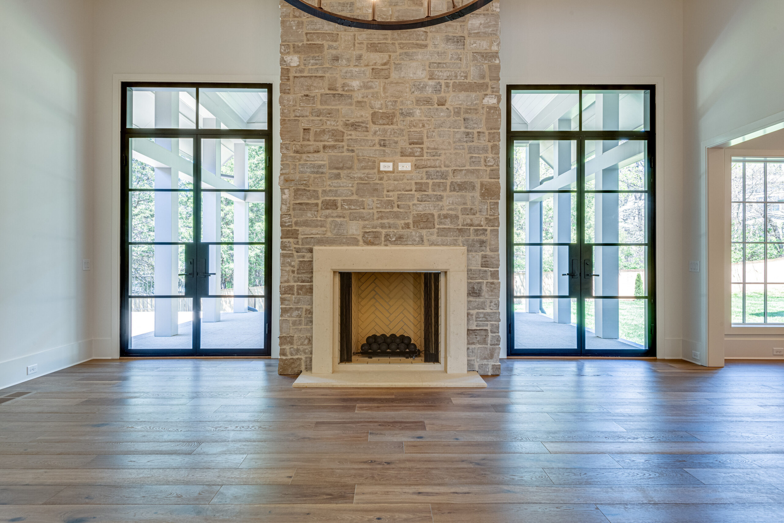 Stone faced fireplace centered between two large glass french doors with black grids