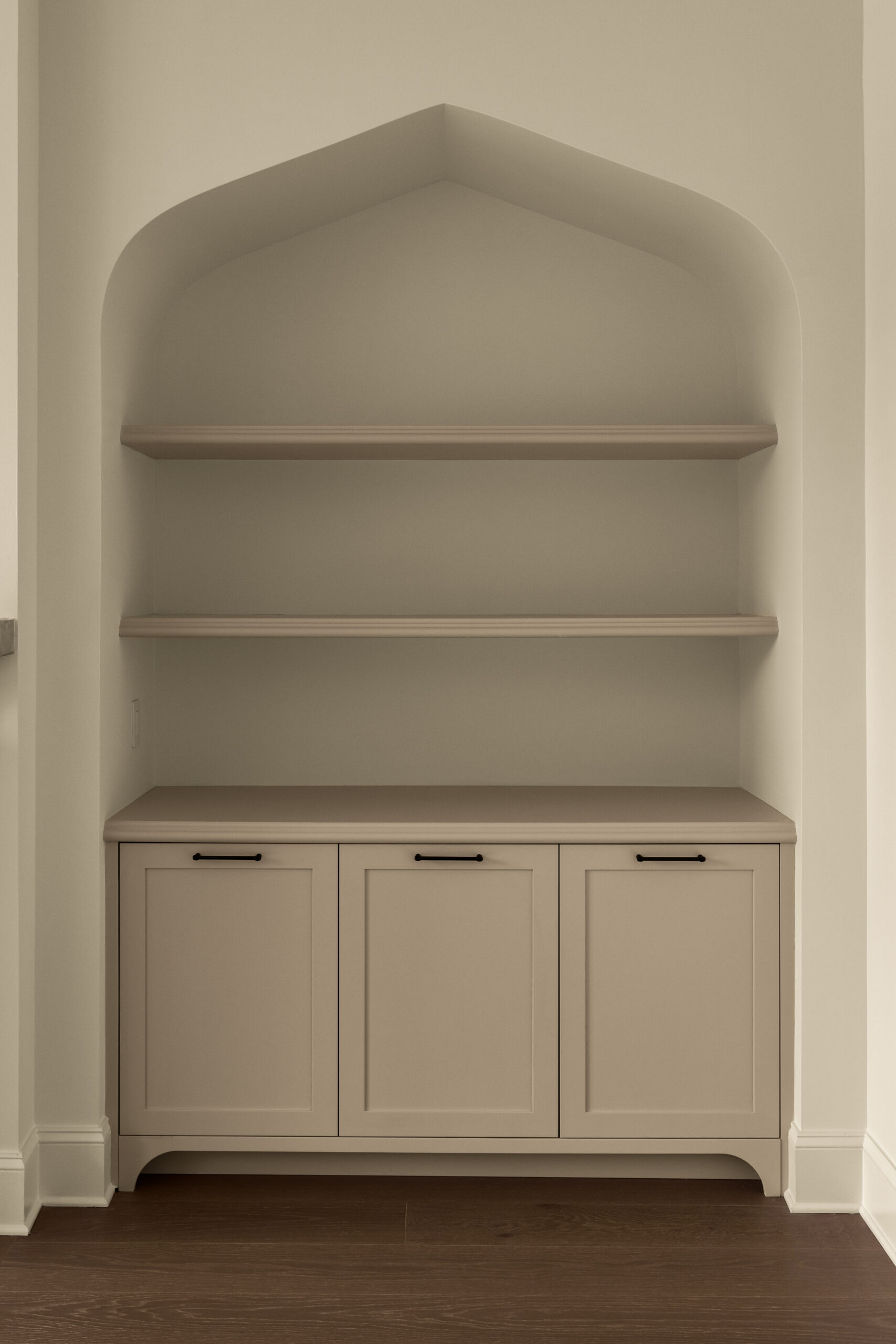 Creamy built-ins with open storage above a double cabinet with a venetian arch in living room