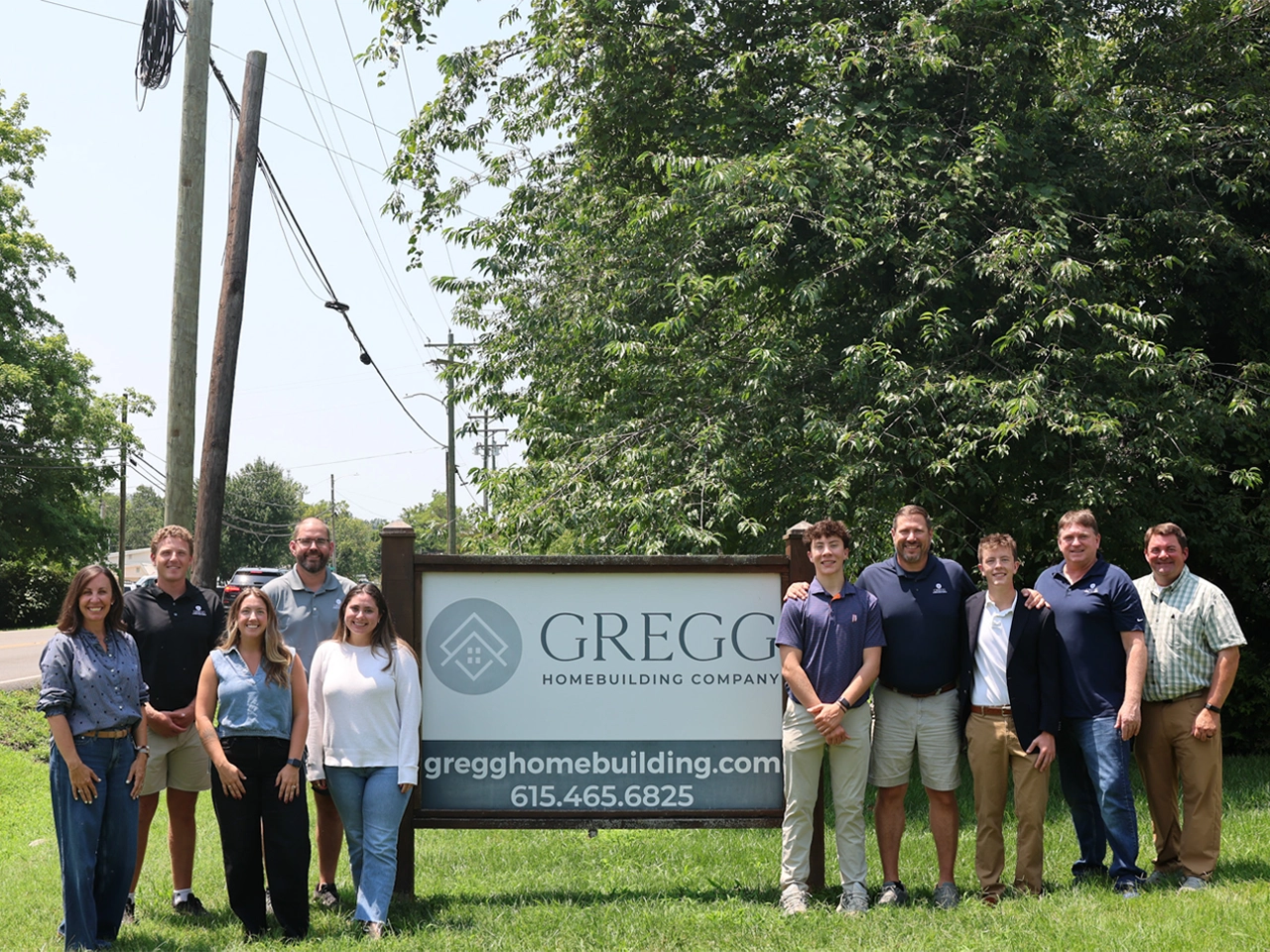 Team group photo of ten people standing together on a grass lawn