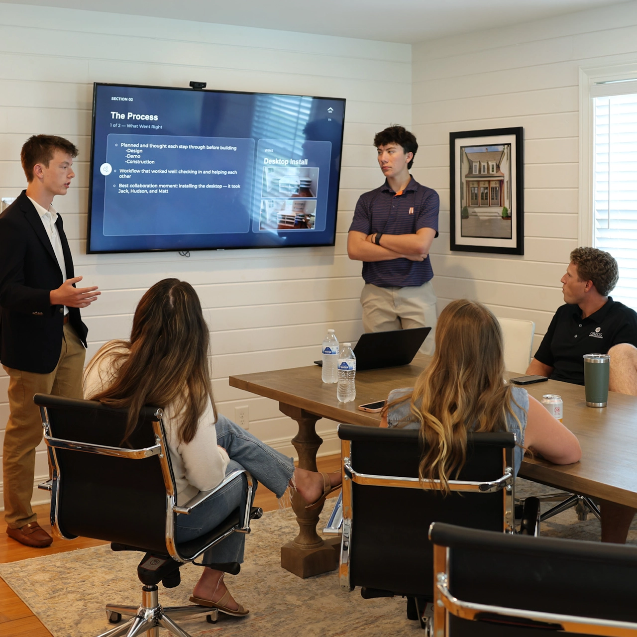 Six team members in a conference room with a presentation on the tv