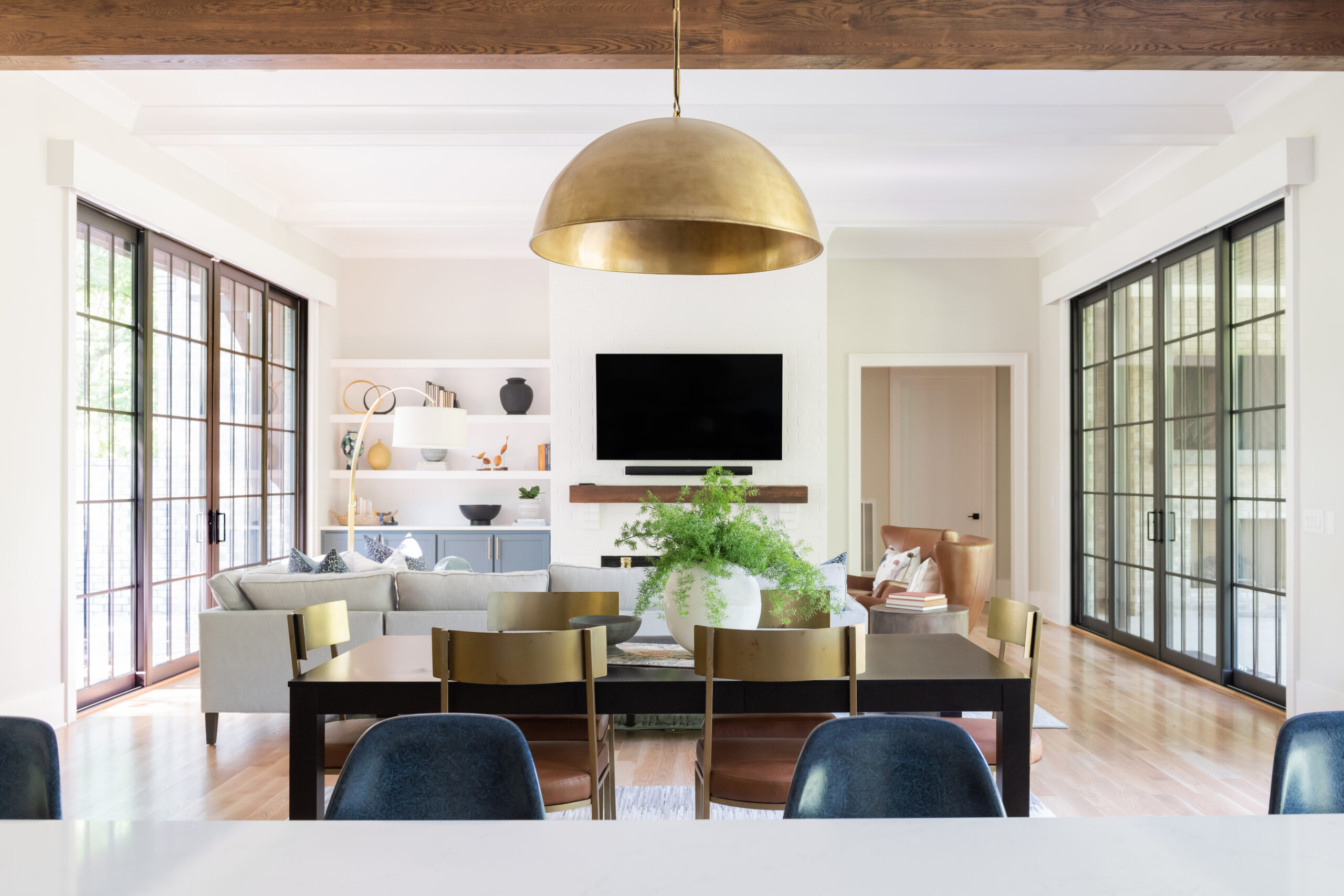 Dining table with gold plated dome chandelier and a view of the family room