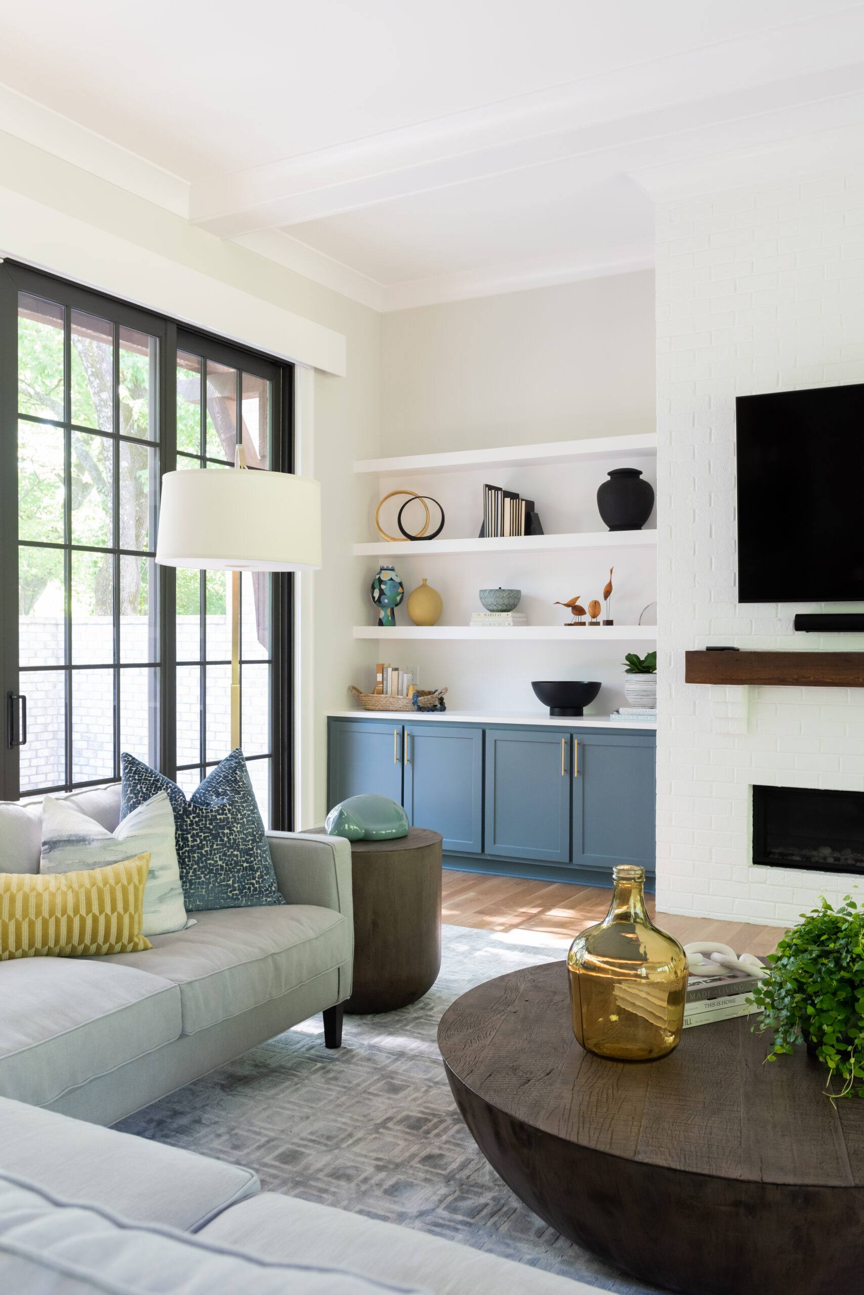 Floor to ceiling black grid window with view of built-in shelving and a partial view of mantle and tv