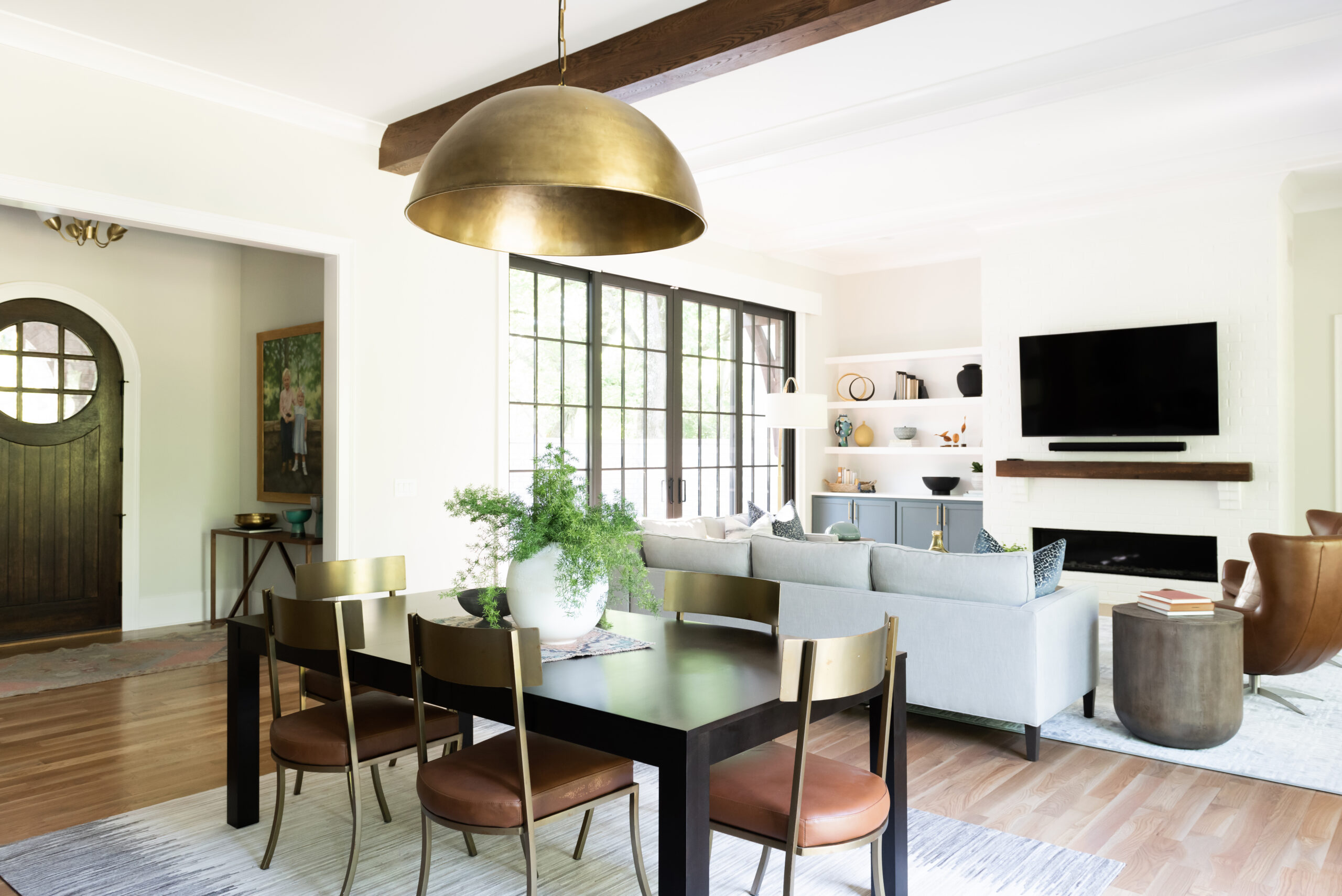 Dining table with gold plated dome chandelier and a view of the family room