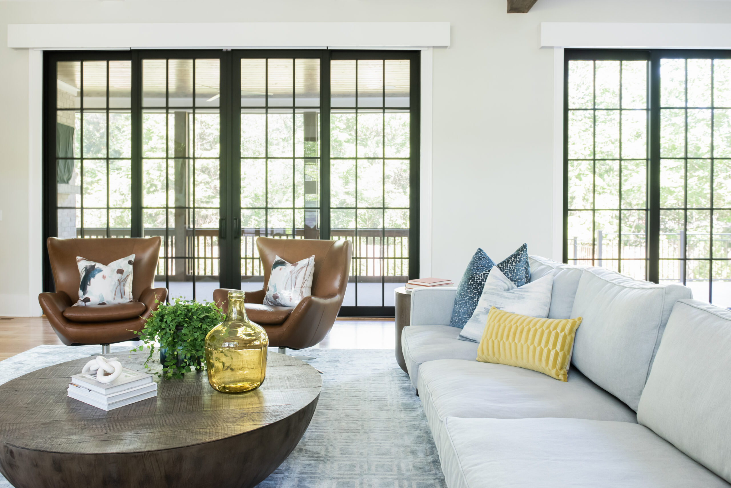 View of couch and leather chairs with white walls and large black grid windows