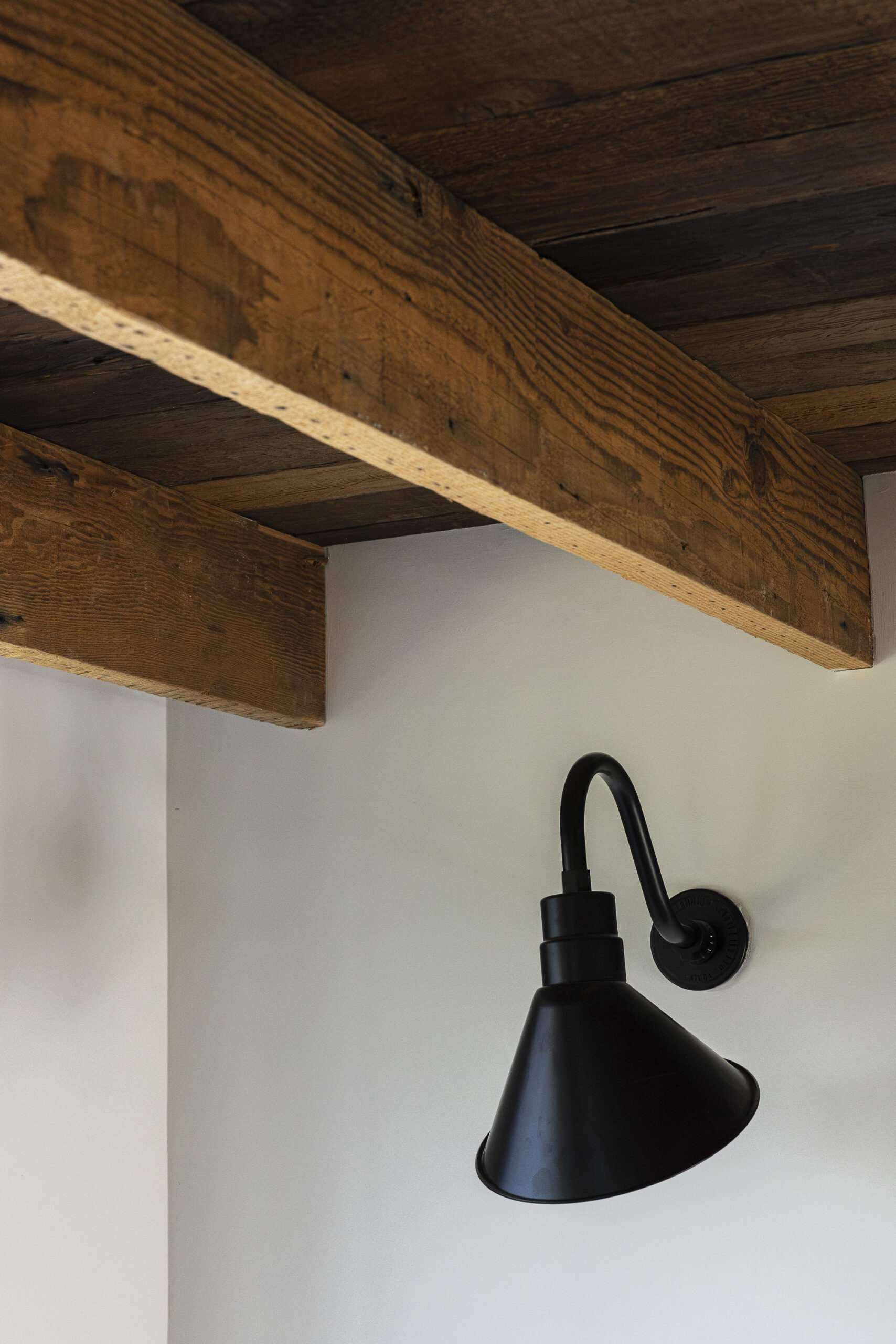 Exposed wood beam ceiling with black metal sconce on the wall