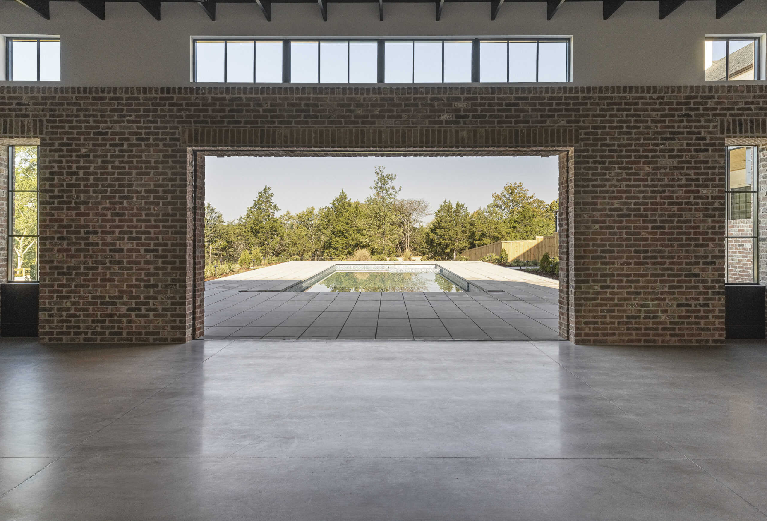 Media room with interior brick walls and large open doorway overlooking a rectangular pool