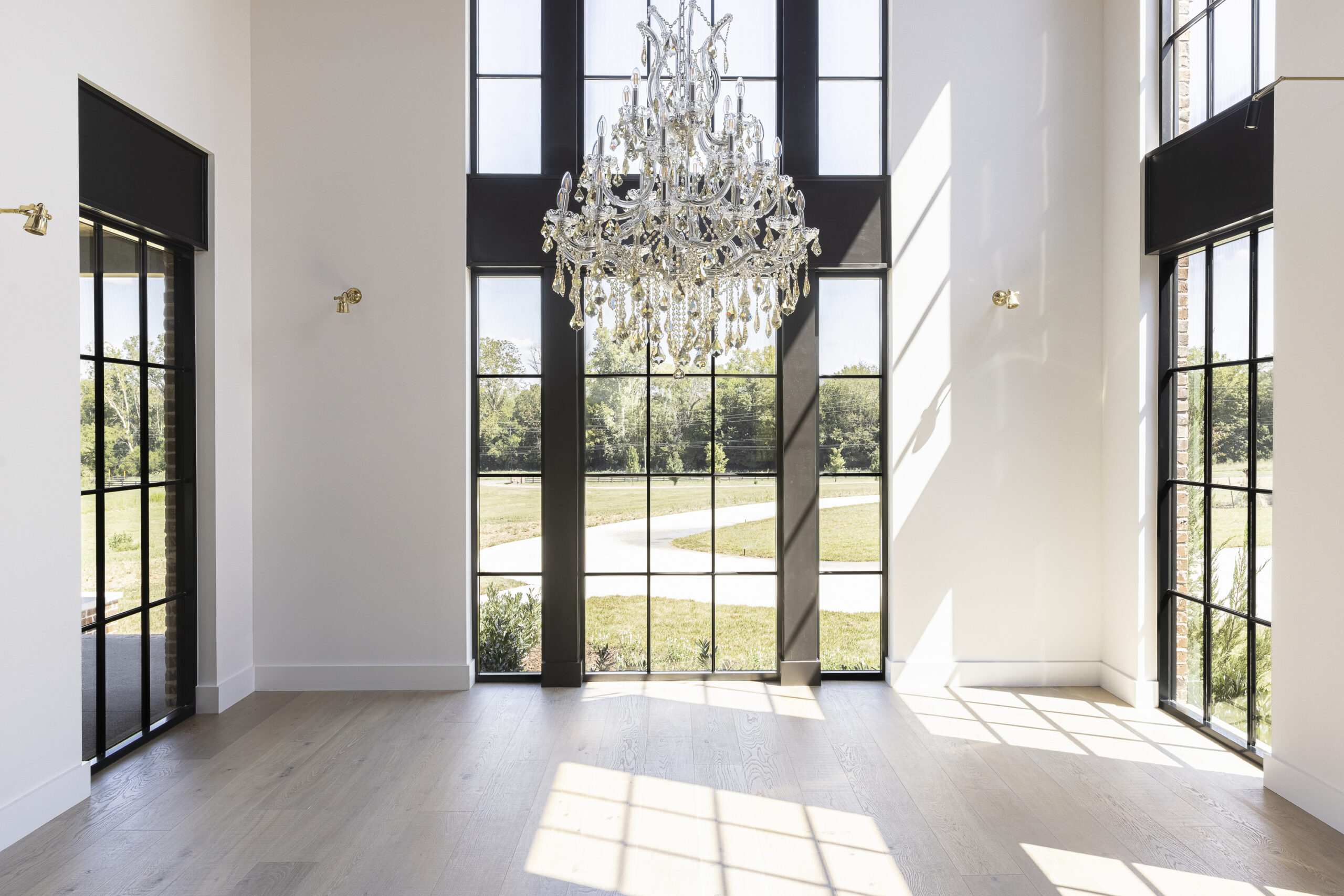 Large floor to ceiling two story window with black grids and a large crystal chandelier
