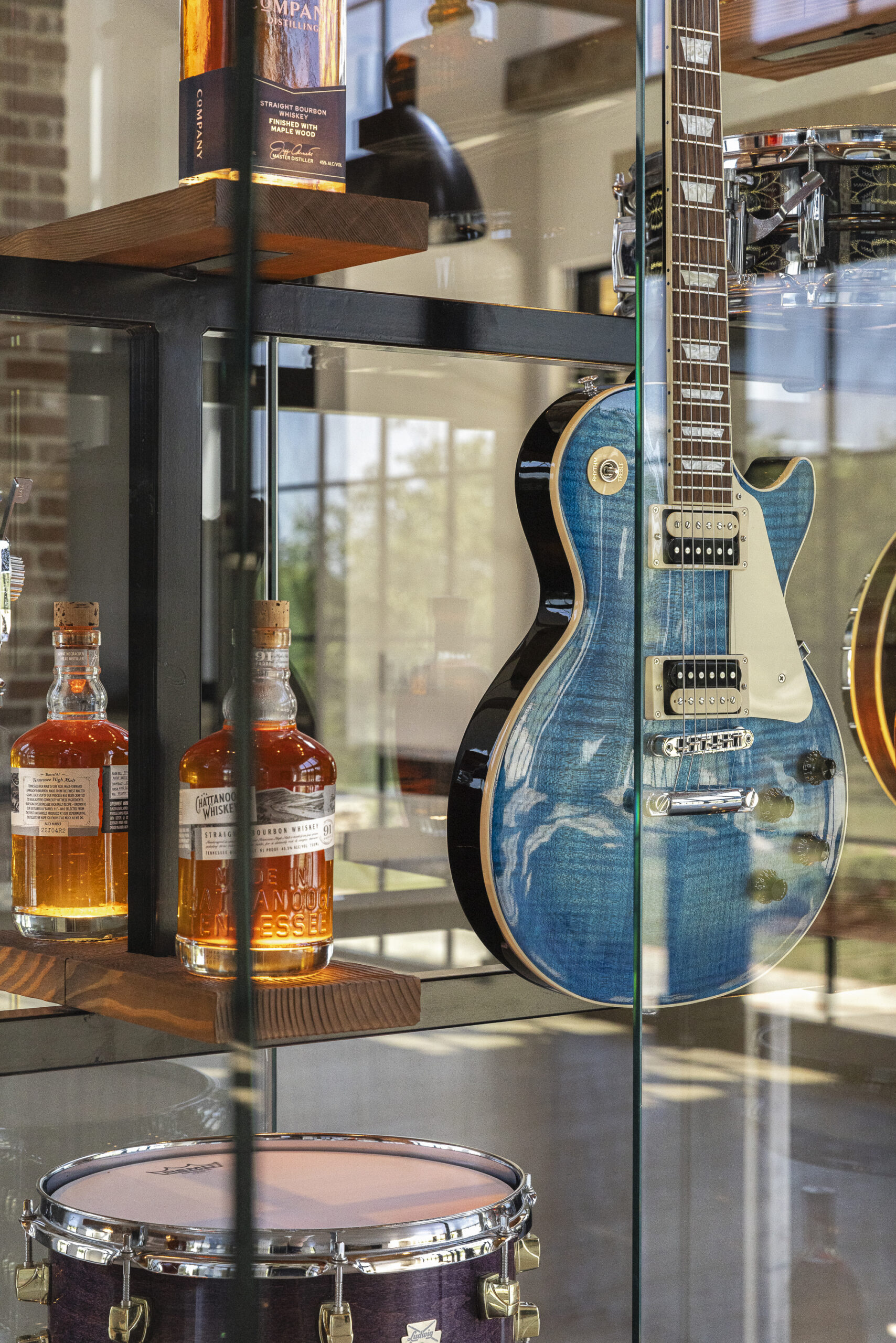 Glass display case featuring a guitar and bottle of bourbon