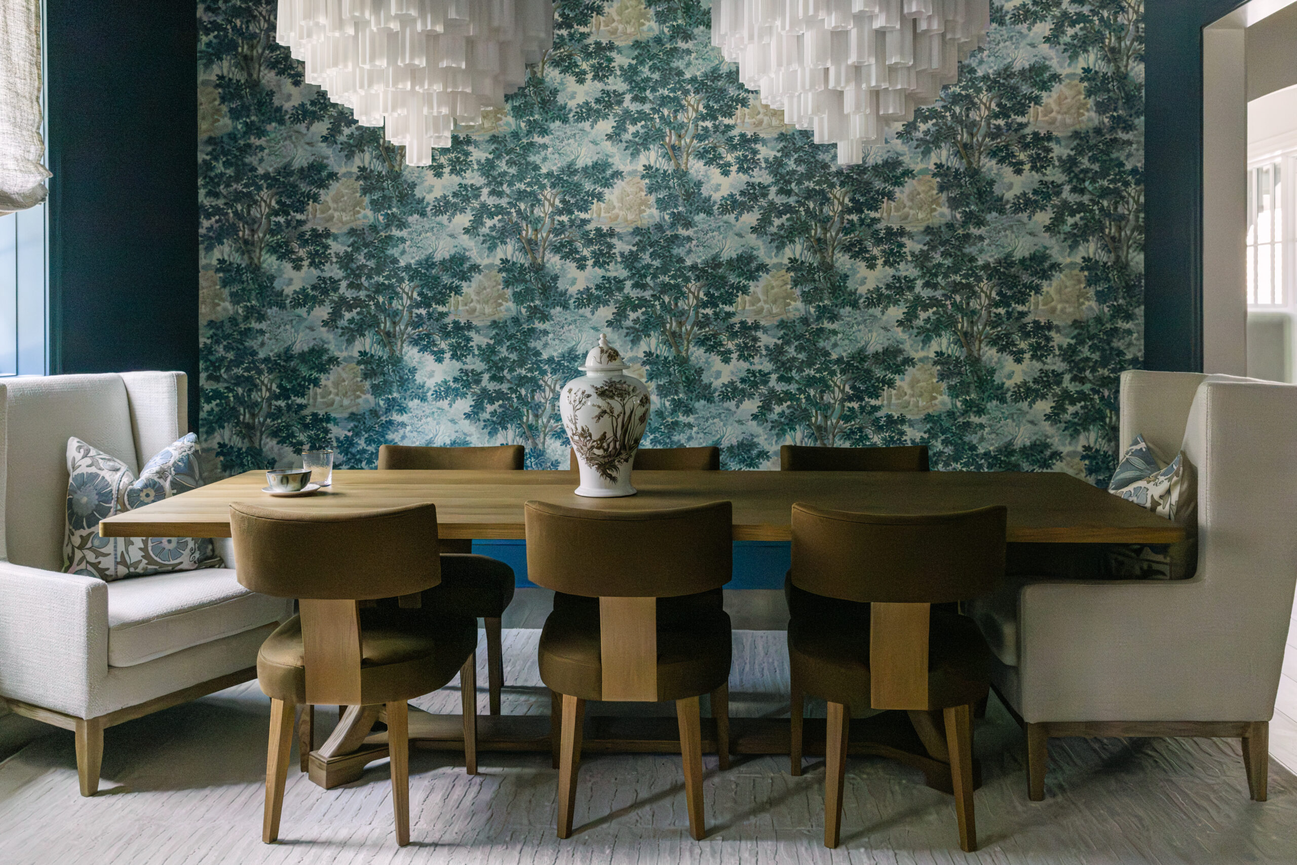 Dining area with modern chairs, two centered chandeliers and blue patterned wall paper