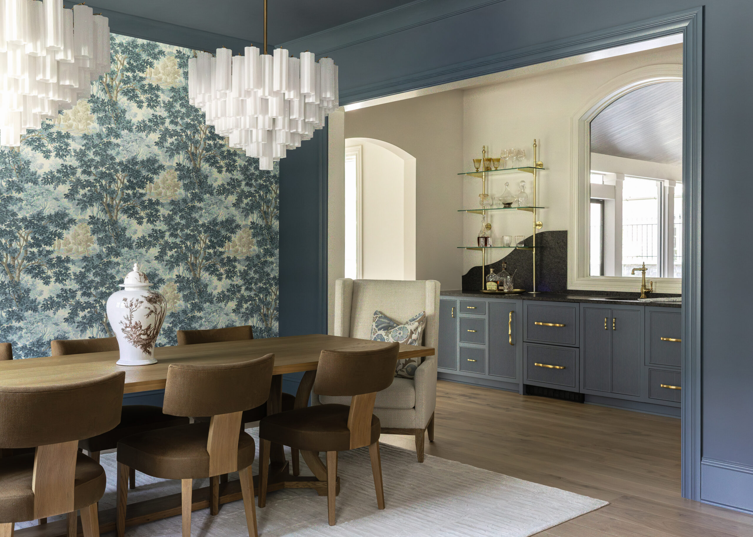 Dining area with modern chairs, two centered chandeliers and blue patterned wall paper