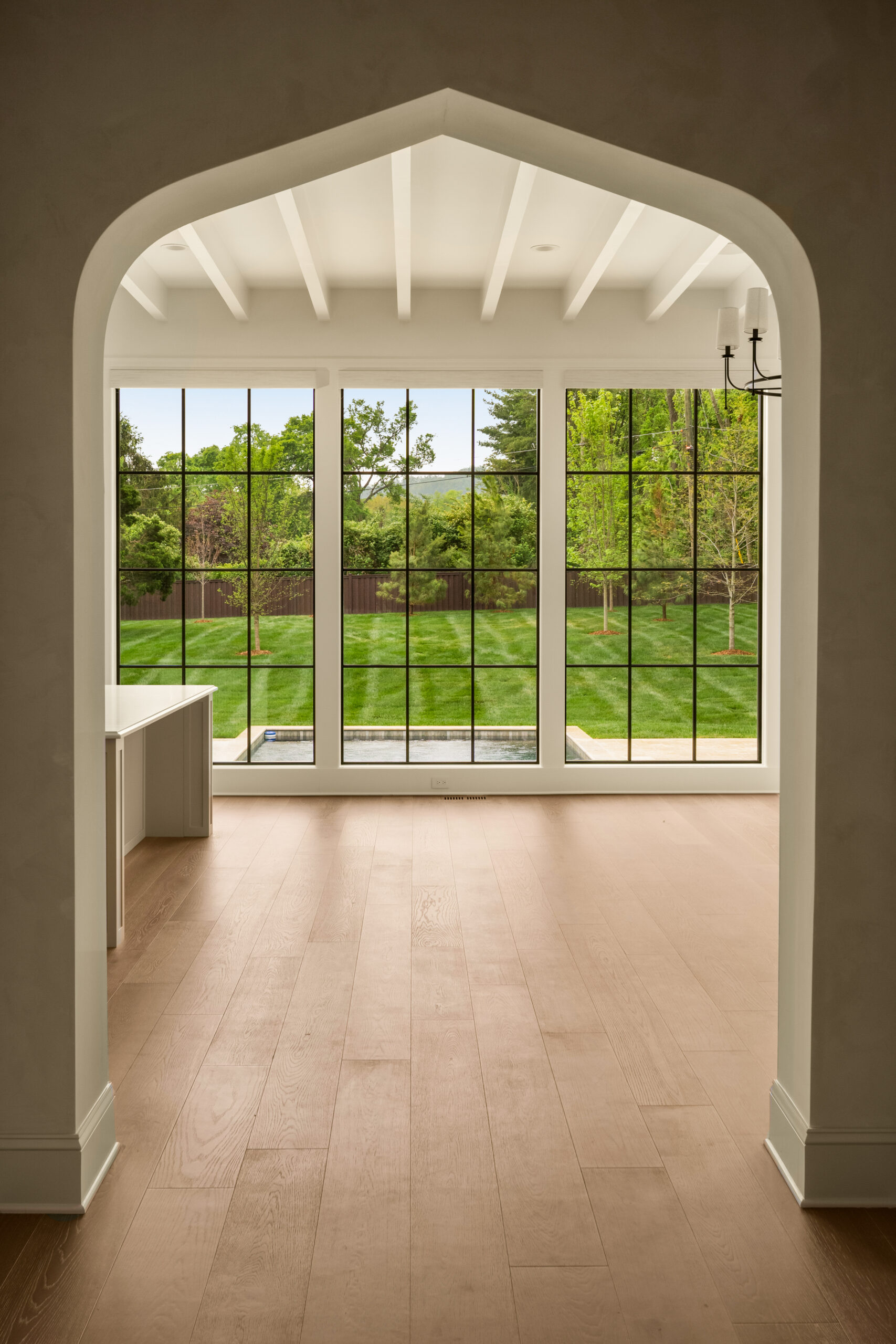 Venetian arch with view of floor to ceiling windows with black grids showing a view of the backyard