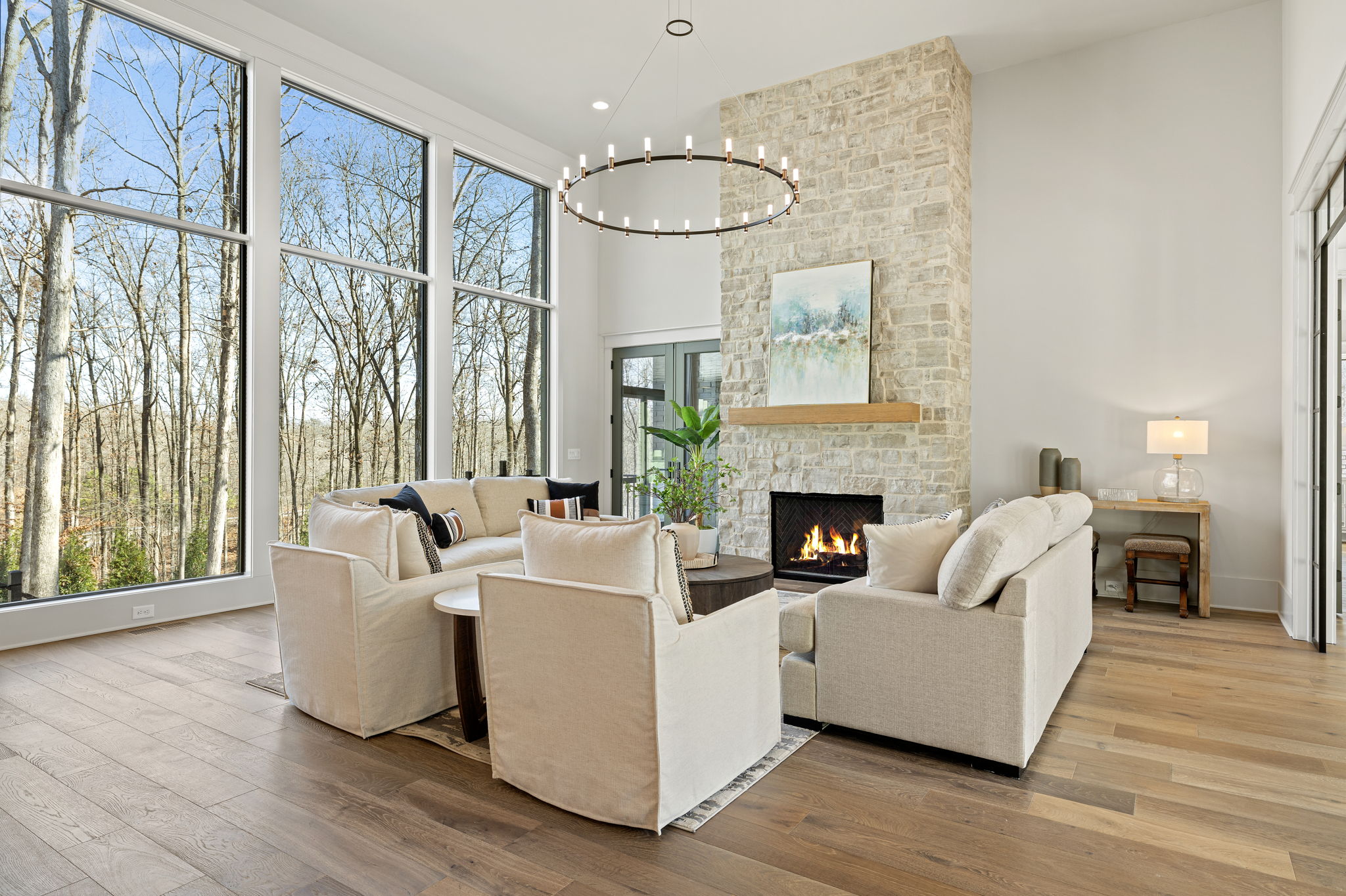 A family room with floor to ceiling stone fireplace and large, floor-to-ceiling black grid windows