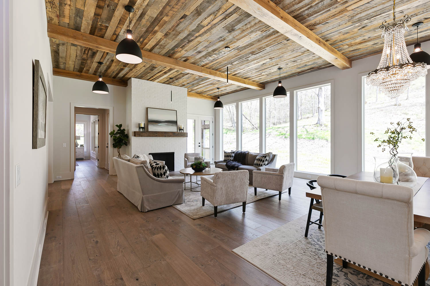 Open floor plan of family room leading into the kitchen with stained, wood paneled ceiling with industrial black spaced lights