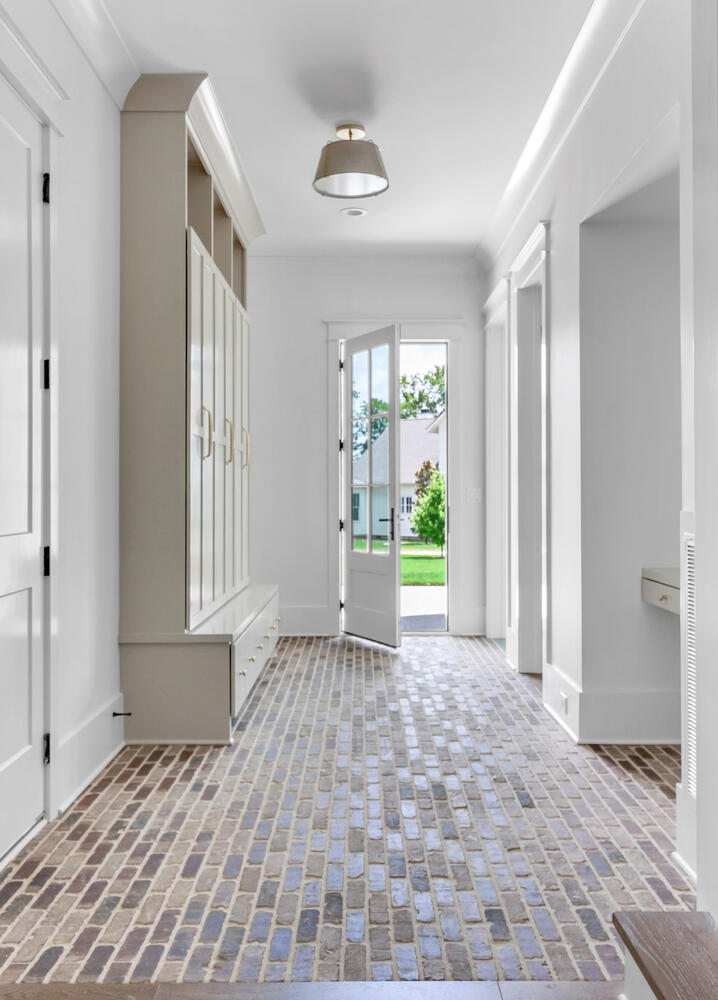Entryway with glass paneled door brick flooring and creamy lockers and builtin mudbench