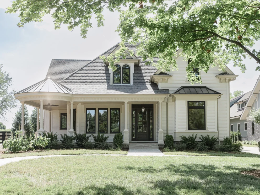 White home exterior with black front door, black-framed windows, and a tree in the front yard