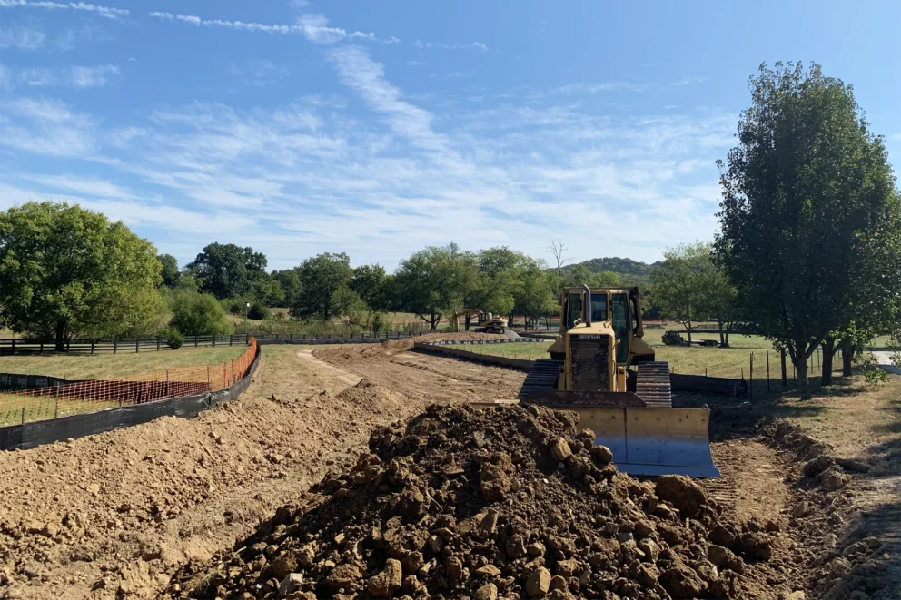 A bulldozer is shoveling dirt in a flat field