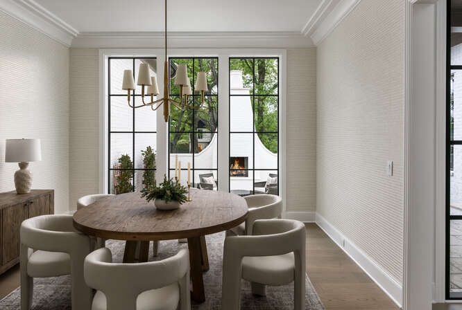 Circular dining table with view of outdoor patio through large black grid windows