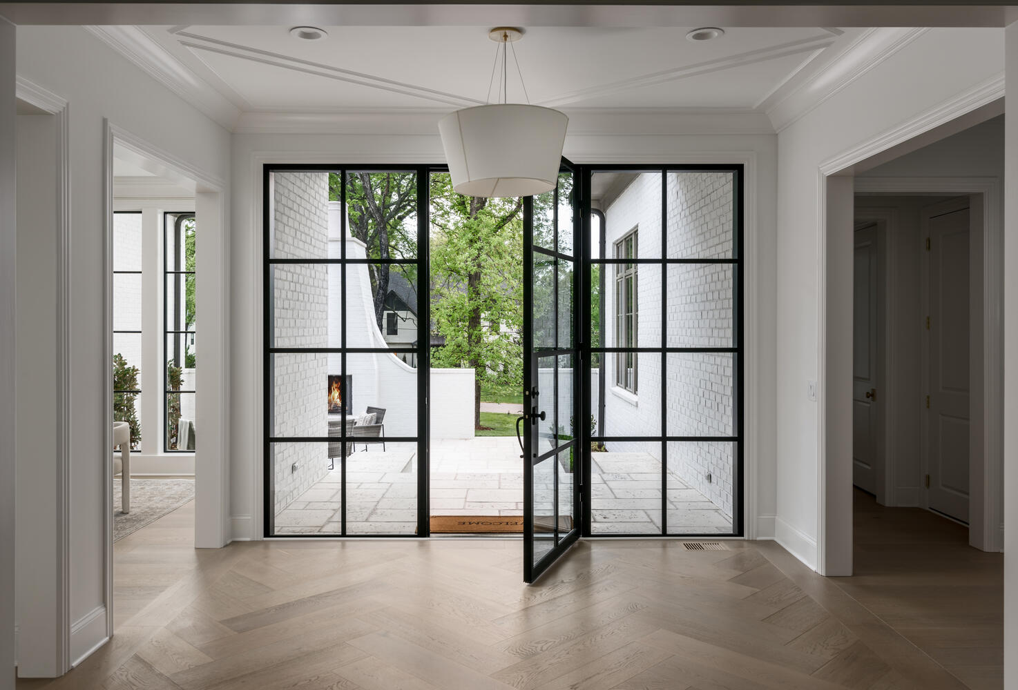 Entryway with large glass door and sidelights with chadelier and herringbone light hardwood flooring